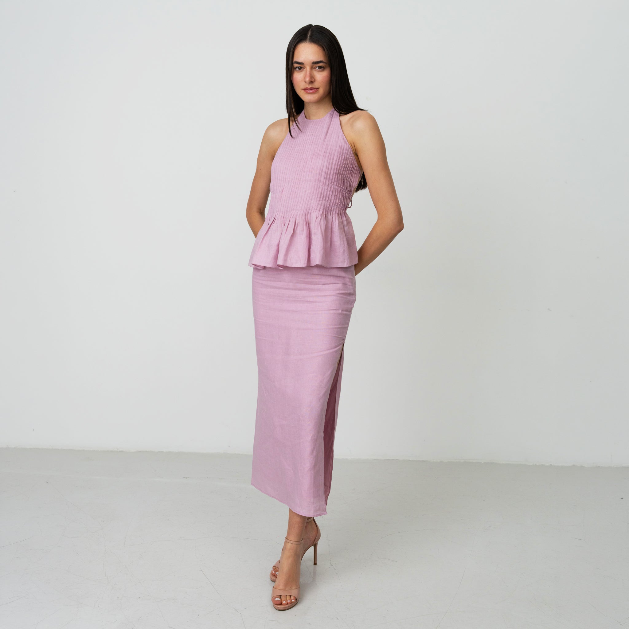 Woman wearing a pink peplum top and skirt set on a white background