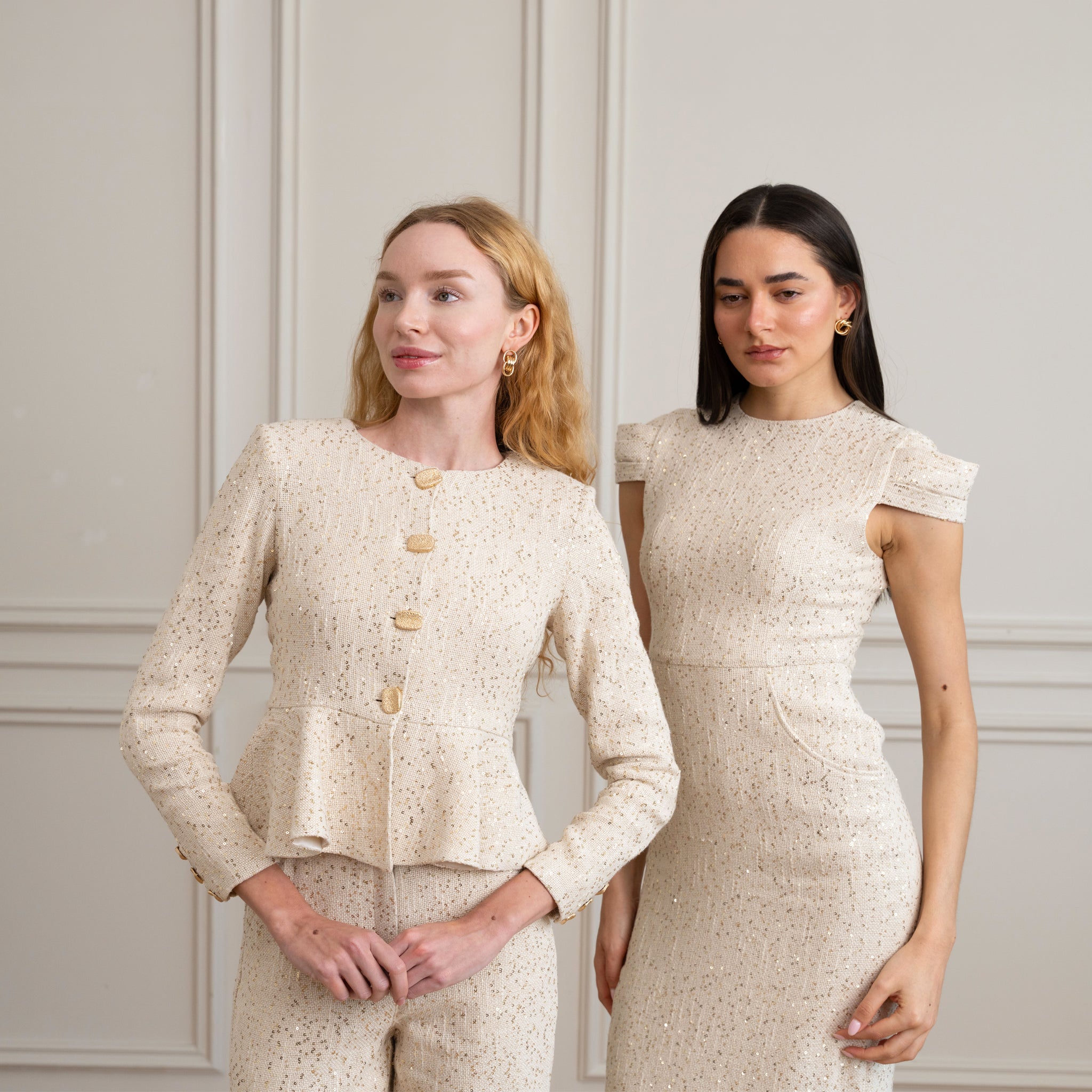 Two women wearing matching beige outfits against a neutral background
