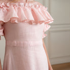 Close-up of a pink dress with ruffled details with self embroidered linen fabric on a neutral background